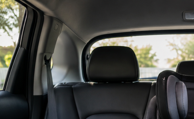 Silla infantil negra instalada en asiento trasero central de auto, destacando posición segura para niños con cinturón de seguridad ajustado.