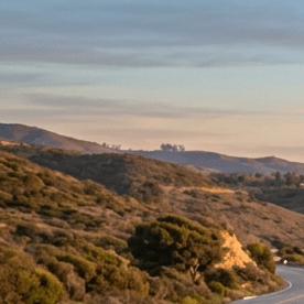 “Tesla Model 3 azul y Tesla Model Y rojo circulando por carretera costera al atardecer, autos eléctricos en carretera panorámica junto al mar en 2026