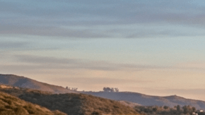“Tesla Model 3 azul y Tesla Model Y rojo circulando por carretera costera al atardecer, autos eléctricos en carretera panorámica junto al mar en 2026
