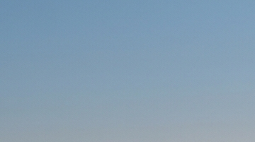 Un SUV eléctrico blanco conduciendo por una autopista al atardecer.