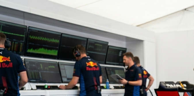 Niño sonriente como director de equipo en garaje de F1 con pista Hot Wheels.