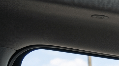 Mujer conduciendo SUV con Android Auto en pantalla grande, copiloto y estación de carga EV al fondo