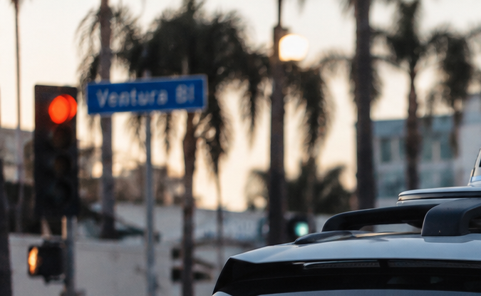 Auto autónomo Waymo circula por avenida de California, imagen relacionada con multas de tránsito, regulación vial y conducción sin conductor.