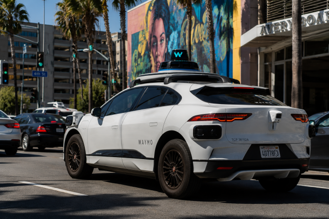 Auto autónomo Waymo circula por avenida de California, imagen relacionada con multas de tránsito, regulación vial y conducción sin conductor.