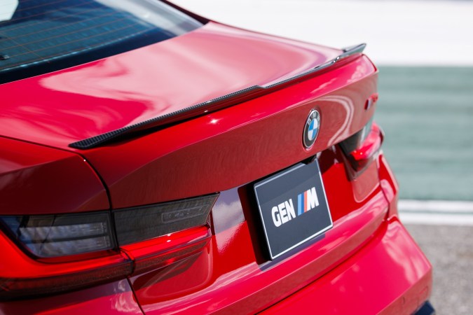 Detalle de alerón trasero BMW M3 CS con logo BMW y placa GEN M en rojo intenso