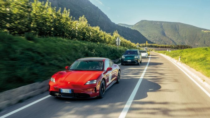 Caravana de Porsche Taycan 4S eléctricos circulando por carretera de montaña