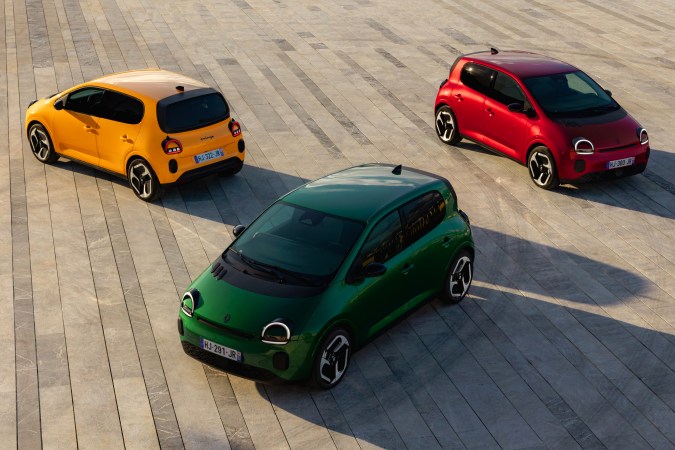 Renault Twingo E-Tech eléctrico en colores verde, amarillo y rojo, coche urbano compacto presentado en plaza abierta.