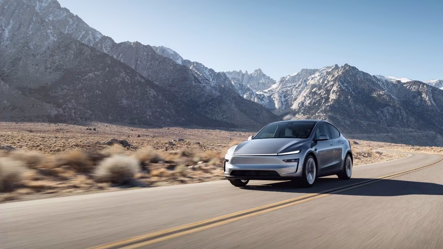 Tesla Model Y 2027 en carretera con montañas nevadas al fondo