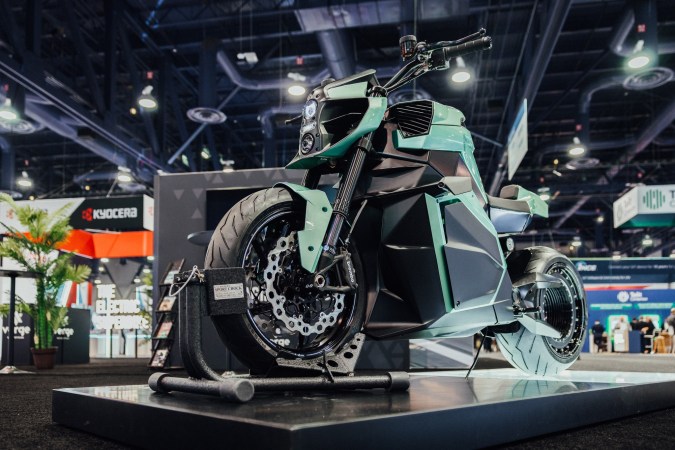 Moto eléctrica Verge TS Ultra negra con diseño futurista y ruedas naranjas, vista lateral en estudio oscuro.
