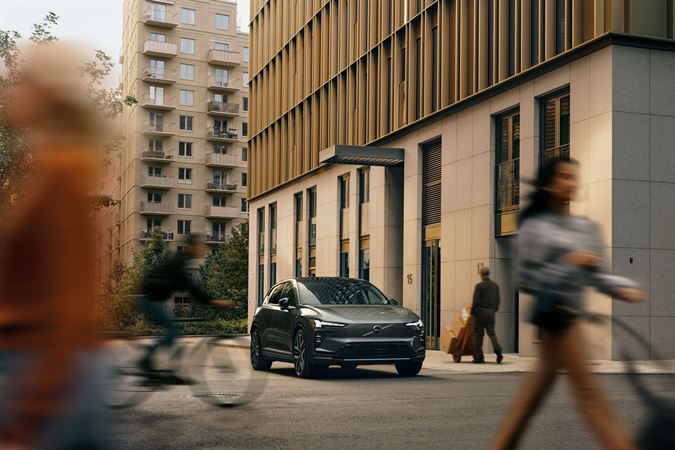 Volvo EX60 estacionado en entorno urbano con peatones y edificios de fondo
