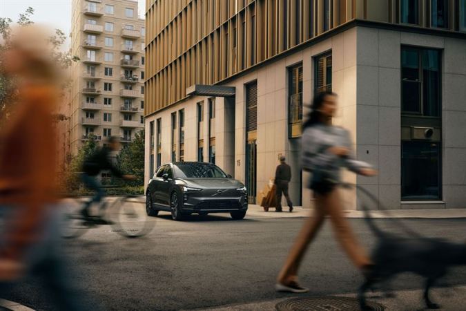 Volvo EX60 estacionado en entorno urbano con peatones y edificios de fondo