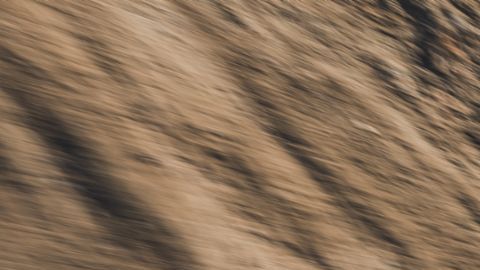 Porsche Macan Eléctrico azul conduciendo en carretera de curvas con montañas al atardecer, vista dinámica