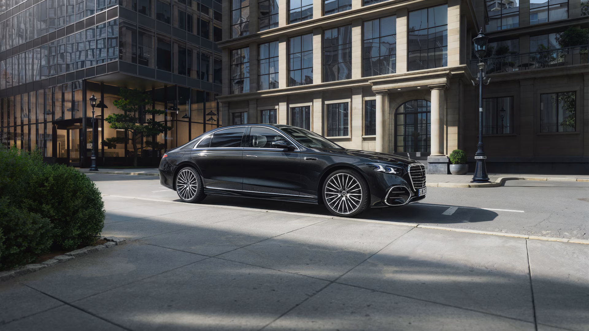 Mercedes-Benz Clase S negra estacionada frente a edificios modernos, sedán premium con diseño sofisticado y rines de lujo.
