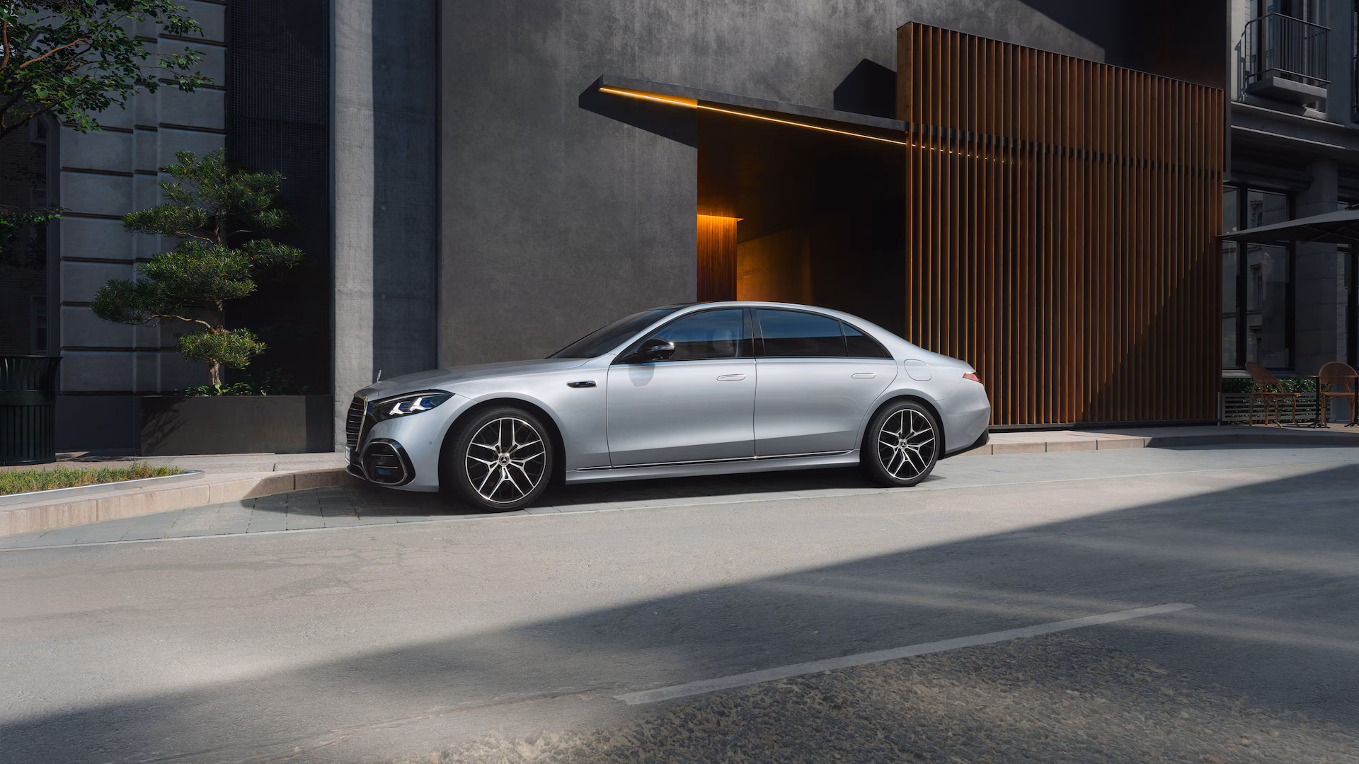 Mercedes-Benz Clase S 2027 plateada, vista lateral en entorno urbano moderno, con líneas aerodinámicas y acabado premium.