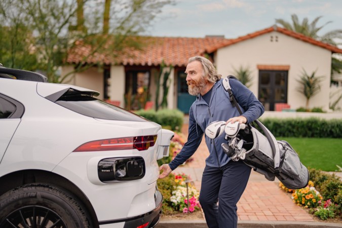 Pasajero con bolsa de golf abordando un robotaxi Waymo en zona residencial