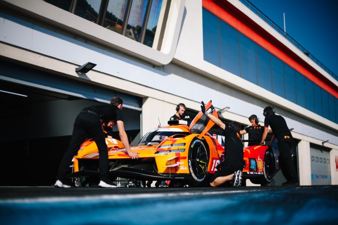 Equipo Genesis Magma Racing preparando hypercar naranja número 15 en pit stop para 24 Horas de Le Mans.
