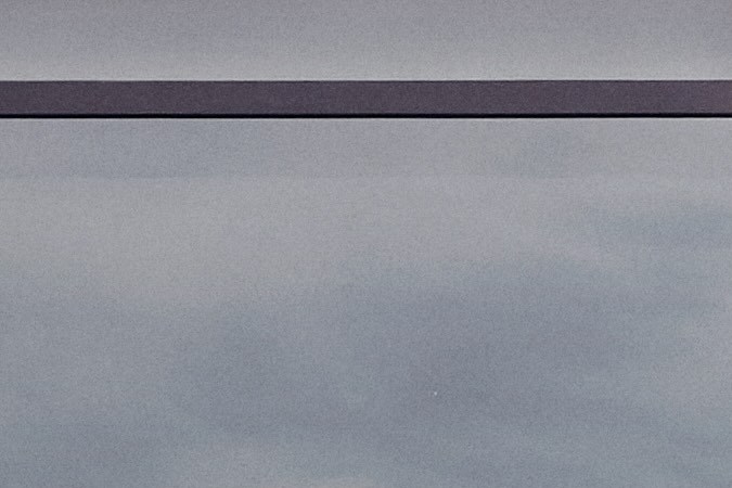 Tres sedanes Lucid Air eléctricos en gris, plata y negro estacionados frente a edificio moderno de la marca.