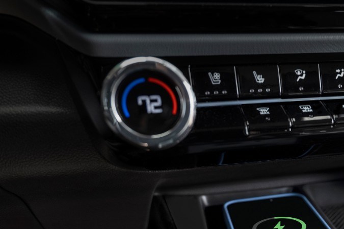 Cargador inalámbrico del Chevrolet Bolt 2027 con smartphone cargando al 75%, detalle del sistema de confort del interior.