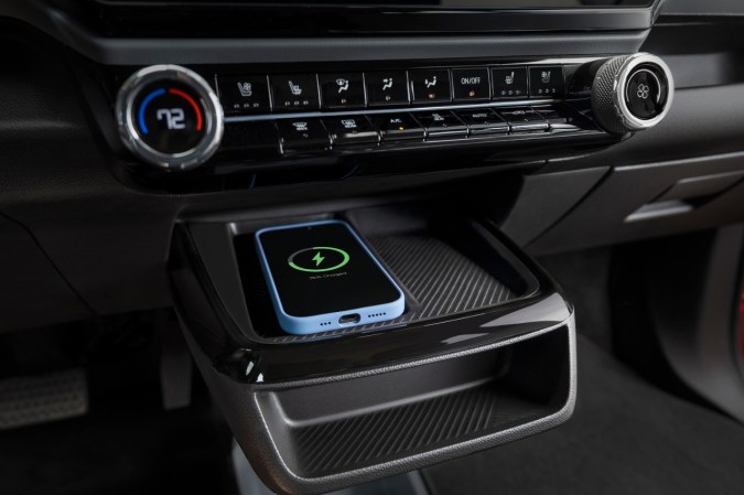 Cargador inalámbrico del Chevrolet Bolt 2027 con smartphone cargando al 75%, detalle del sistema de confort del interior.