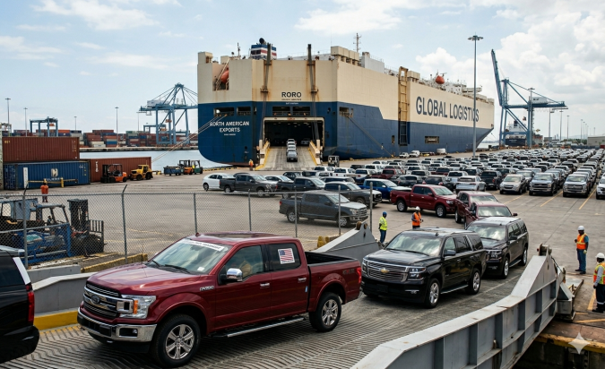 Un puerto con cientos de vehículos norteamericanos, incluyendo una pickup Ford F-150 roja y un SUV Chevrolet Tahoe negro en primer plano