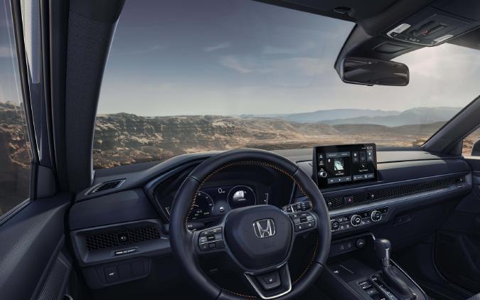Interior del Honda CR-V 2026 con asientos de cuero, pantalla táctil y volante deportivo, vista panorámica del habitáculo.