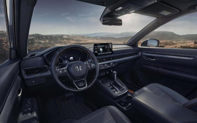 Interior del Honda CR-V 2026 con asientos de cuero, pantalla táctil y volante deportivo, vista panorámica del habitáculo.
