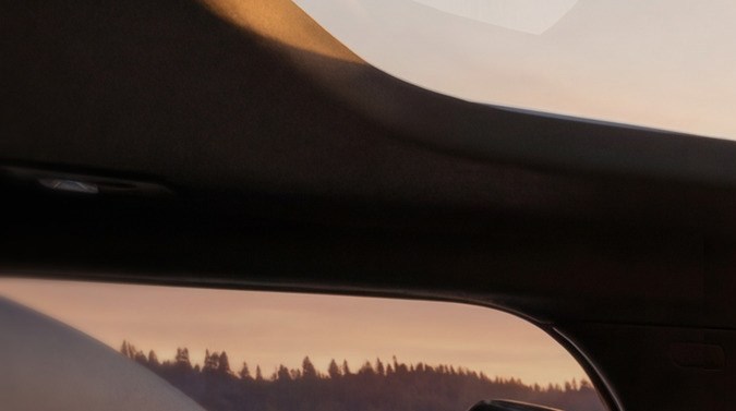 Interior del Jeep Grand Cherokee Overland 2027, asientos de cuero y tablero tecnológico, vista al lago al atardecer, SUV premium para viajes de lujo.