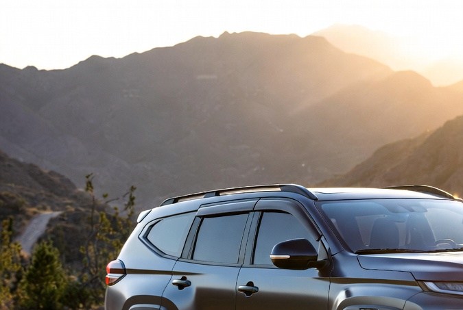 Mitsubishi Montero SUV gris oscuro todoterreno en camino rocoso de montaña al atardecer, con luces LED encendidas.