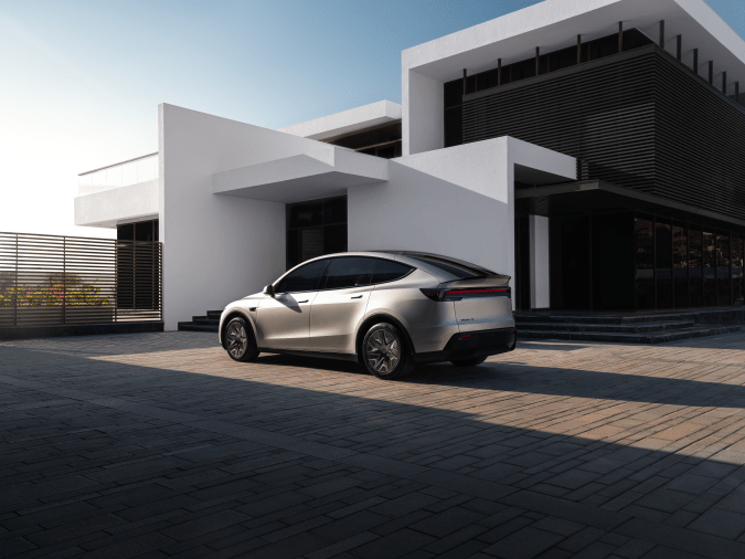 Tesla Model Y plateado visto desde atrás frente a edificio moderno