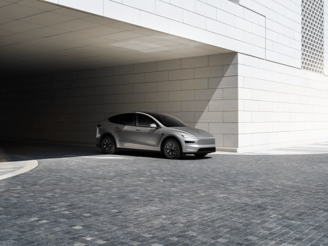 Tesla Model Y plateado estacionado bajo estructura de concreto