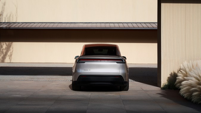 Vista trasera del Tesla Model Y junto a pared y vegetación