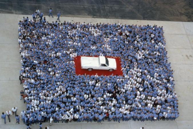 Histórica foto con trabajadores japoneses formando la bandera de Japón alrededor de una pickup Nissan Frontier blanca.