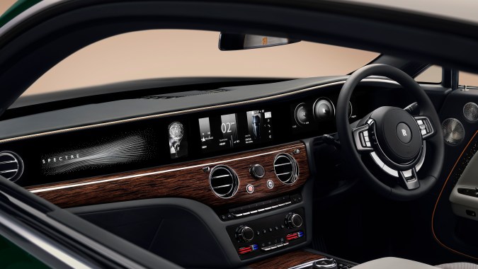 Salpicadero y volante del Rolls-Royce Spectre Series II, pantallas digitales, madera noble y detalles metálicos en el interior del coupé eléctrico de lujo.