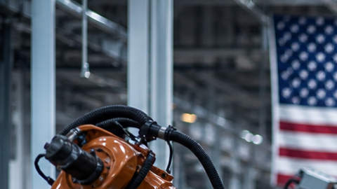Robots industriales ensamblando chasis de auto en moderna planta automotriz integrada de Norteamérica con banderas T-MEC USMCA.