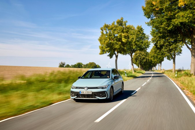 Volkswagen Golf GTE híbrido enchufable azul claro circulando por carretera rural al atardecer, vista dinámica frontal.
