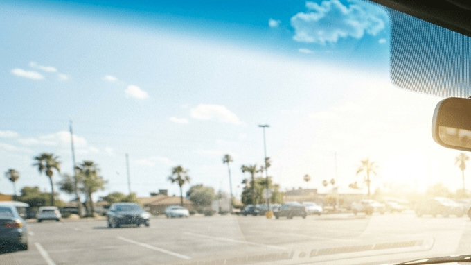 Mujer sofocada activando el aire acondicionado del coche en día caluroso, interior con sol fuerte en estacionamiento