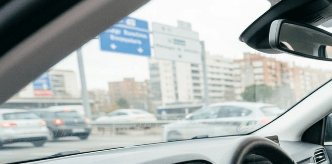Hombre conduciendo y mujer abrochándose el cinturón de seguridad en auto moderno con alerta encendida en el tablero.