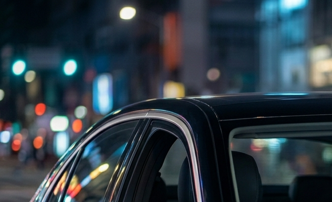 Mujer dentro de auto moderno en ciudad nocturna, preocupada por vigilancia, privacidad y cámaras en vehículos conectados.