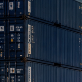 Pickup, SUV y deportivo estadounidense en puerto industrial, listos para exportación junto a contenedores y buque carguero.