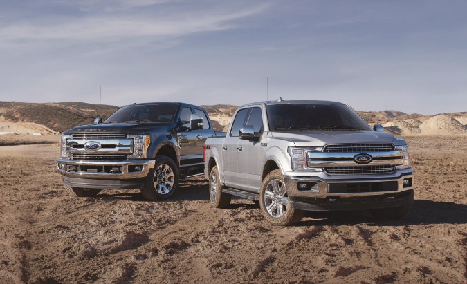 Ford F-150 y Super Duty pickup trucks estacionados en paisaje desértico. Potentes camionetas Ford lado a lado.