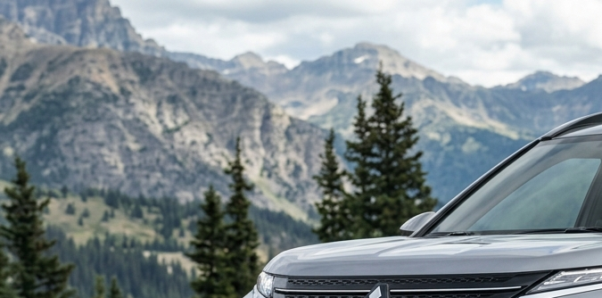 Nuevo Mitsubishi Montero 2026 gris plata en posición frontal sobre roca, con faros LED y montañas nevadas de fondo.
