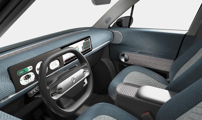 Interior moderno de Telo Truck con tablero digital, asientos premium y acabados en tonos azul gris.