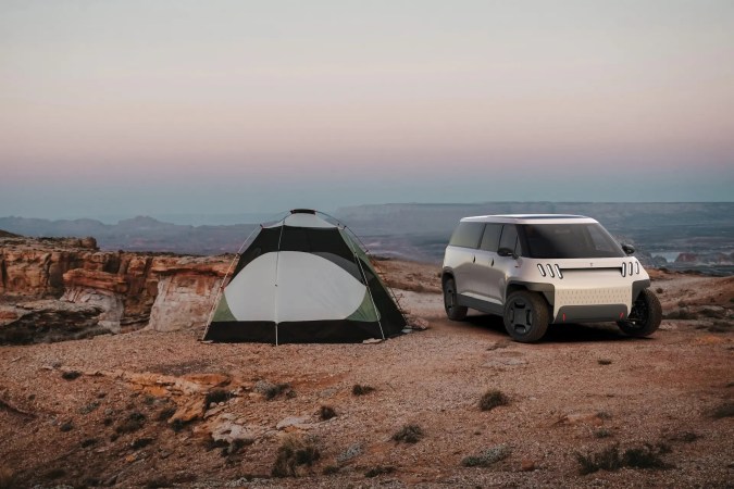 Telo Truck plateada en paisaje desértico con tienda de campaña, ideal para aventuras off-road.