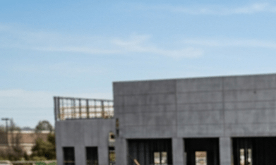 Trabajadores cargando furgonetas en obra de construcción: Ford Transit, Ram ProMaster y Mercedes Sprinter con puertas abiertas.