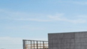 Trabajadores cargando furgonetas en obra de construcción: Ford Transit, Ram ProMaster y Mercedes Sprinter con puertas abiertas.