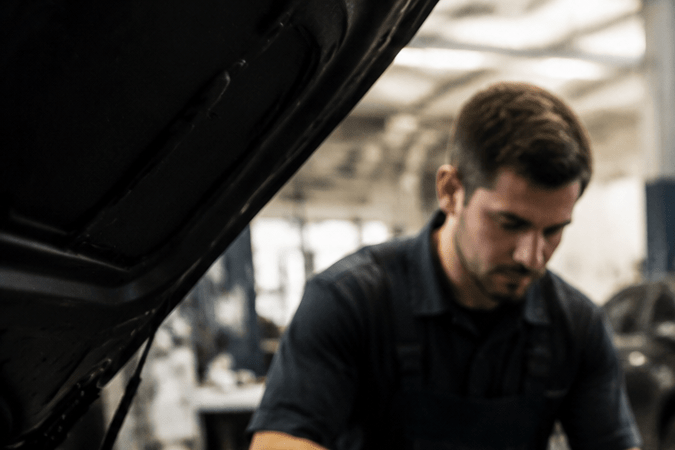 Mecánico usa tableta y software de diagnóstico en taller automotriz para reparar motor de auto moderno