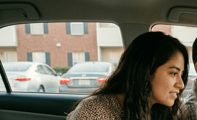 Pareja de nuevos residentes hispanos mudándose a apartamento con documentos y seguro de auto para inmigrantes en Estados Unidos.
