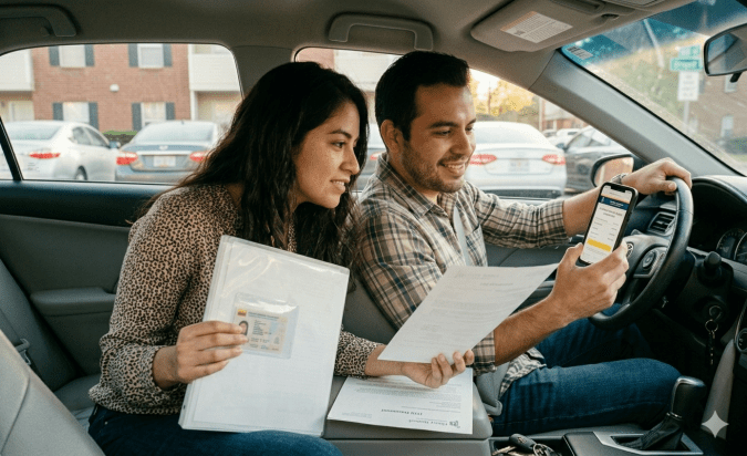 Pareja de nuevos residentes hispanos mudándose a apartamento con documentos y seguro de auto para inmigrantes en Estados Unidos.