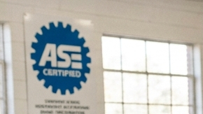 Mecánico certificado ASE explica reporte de salud vehicular a cliente en taller de reparación de autos
