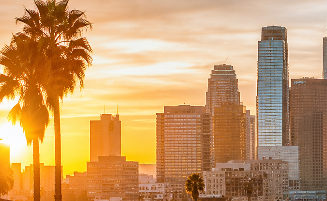 Atasco masivo en la 110 South Los Ángeles al atardecer, tráfico intenso con palmeras y rascacielos de downtown